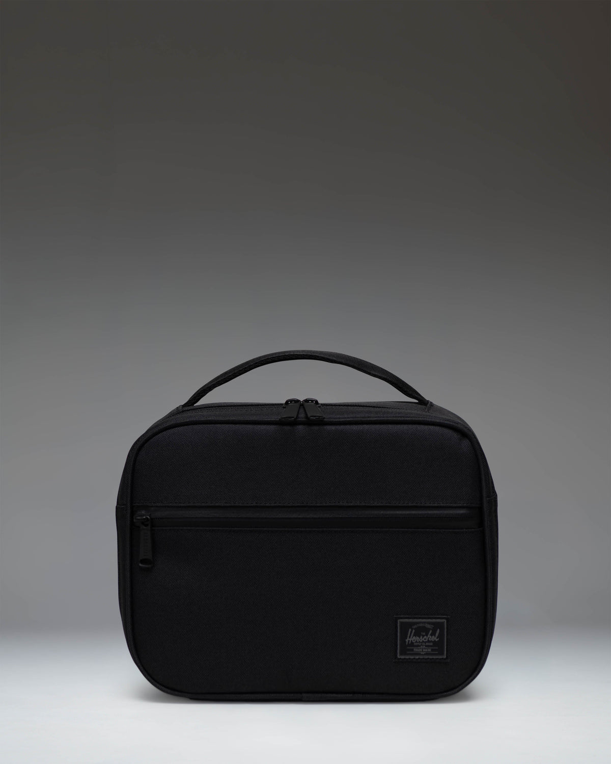 Herschel Supply Co. Pop Quiz Lunch Box in Black Tonal, showing the front view with a zippered pocket and top handle.