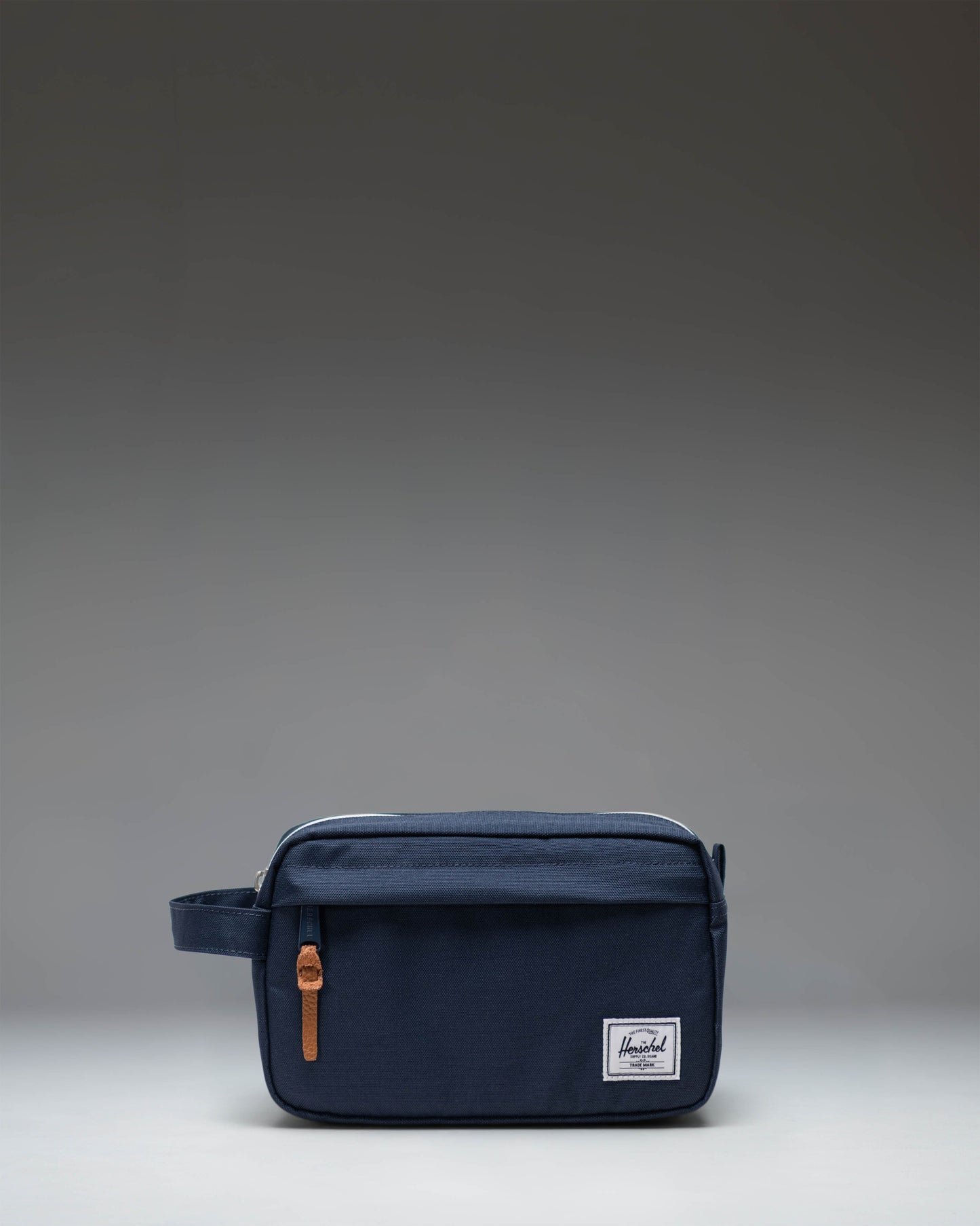 Herschel Supply Co. Chapter Travel Kit in navy blue, showing a side view of the structured travel pouch with a carrying handle.