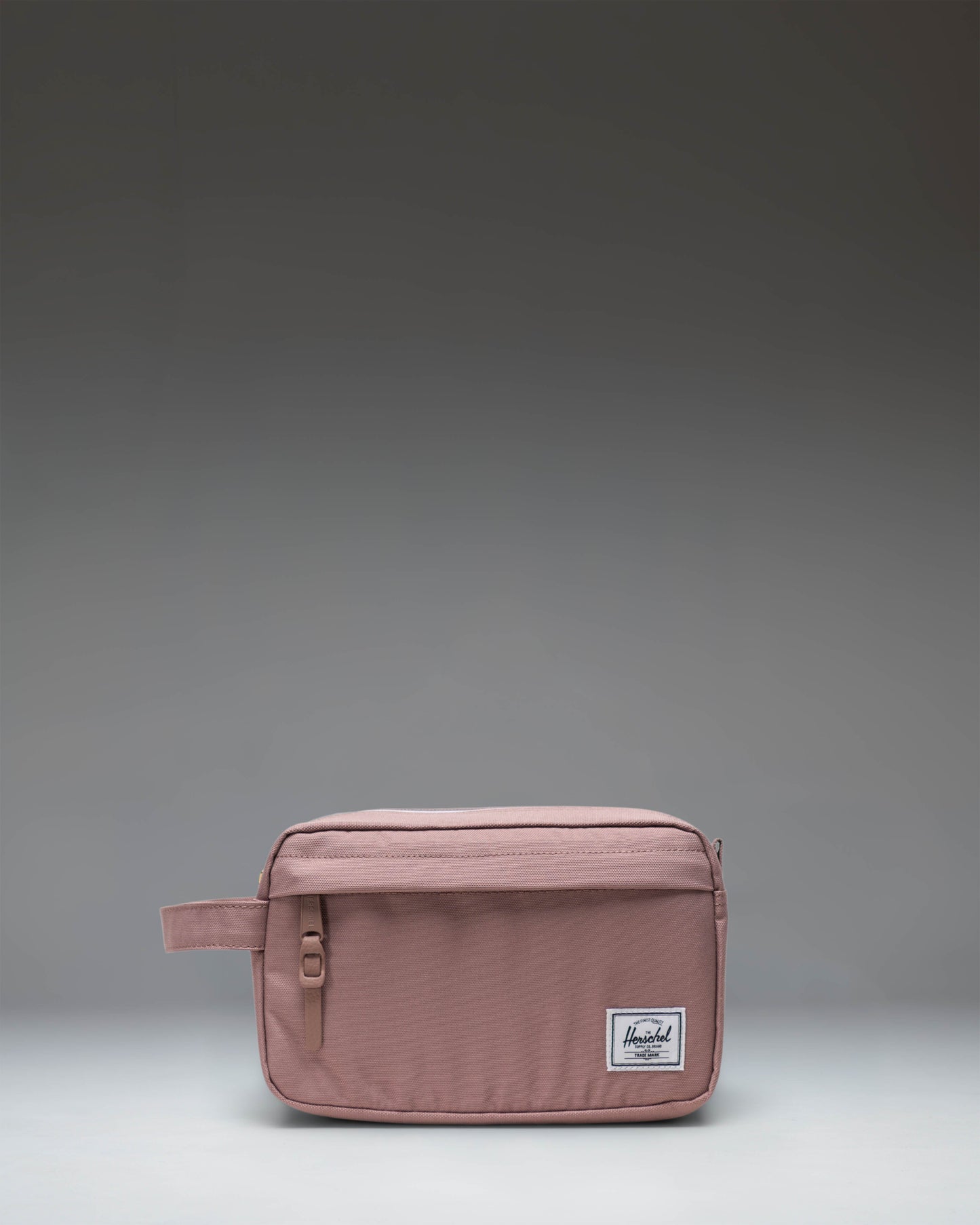 Herschel Supply Co Chapter Travel Kit in Ash Rose, a compact toiletry bag with a carrying handle and front zipper pocket.