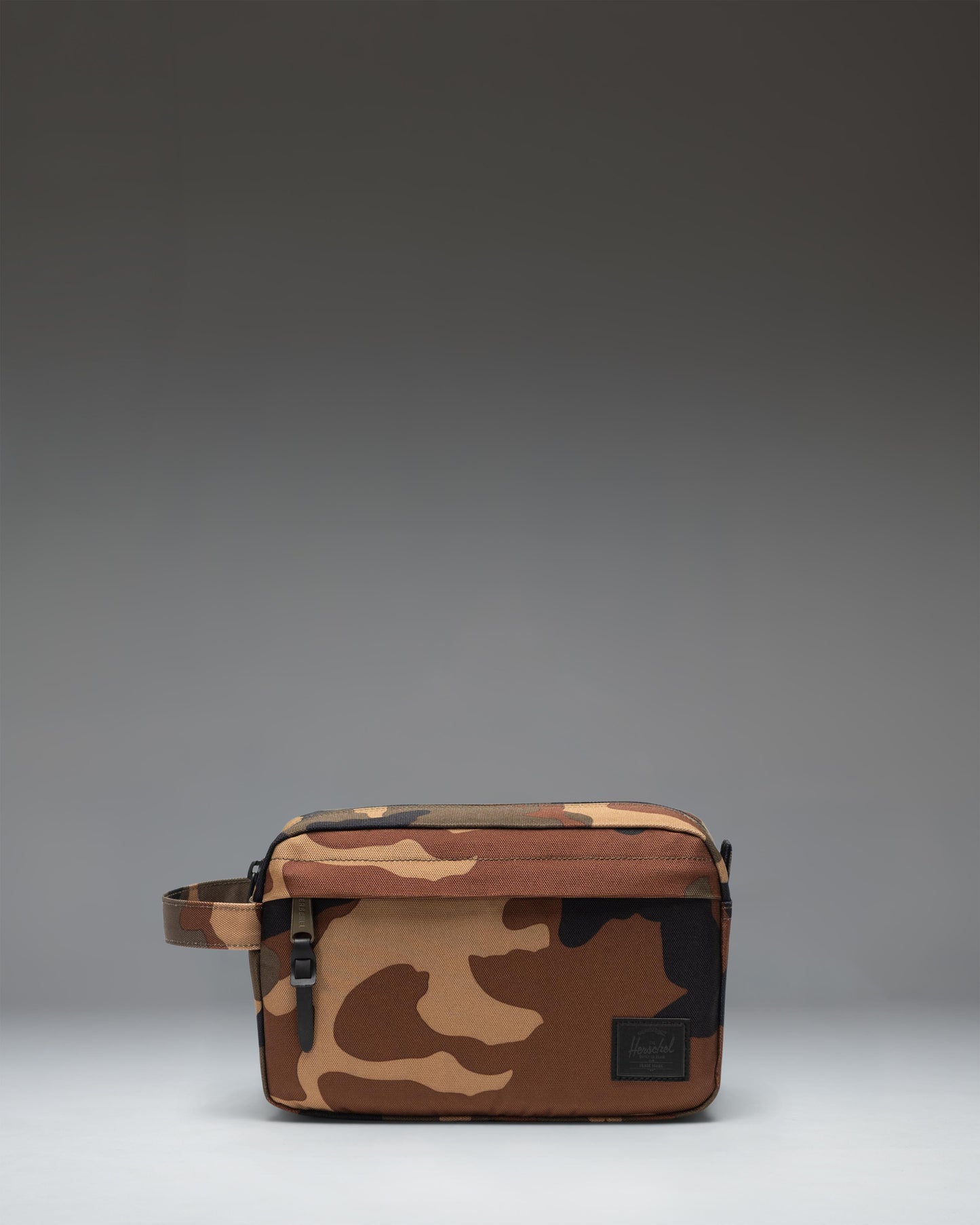 Herschel Supply Co. Chapter Travel Kit in woodland camo featuring a black brand label.