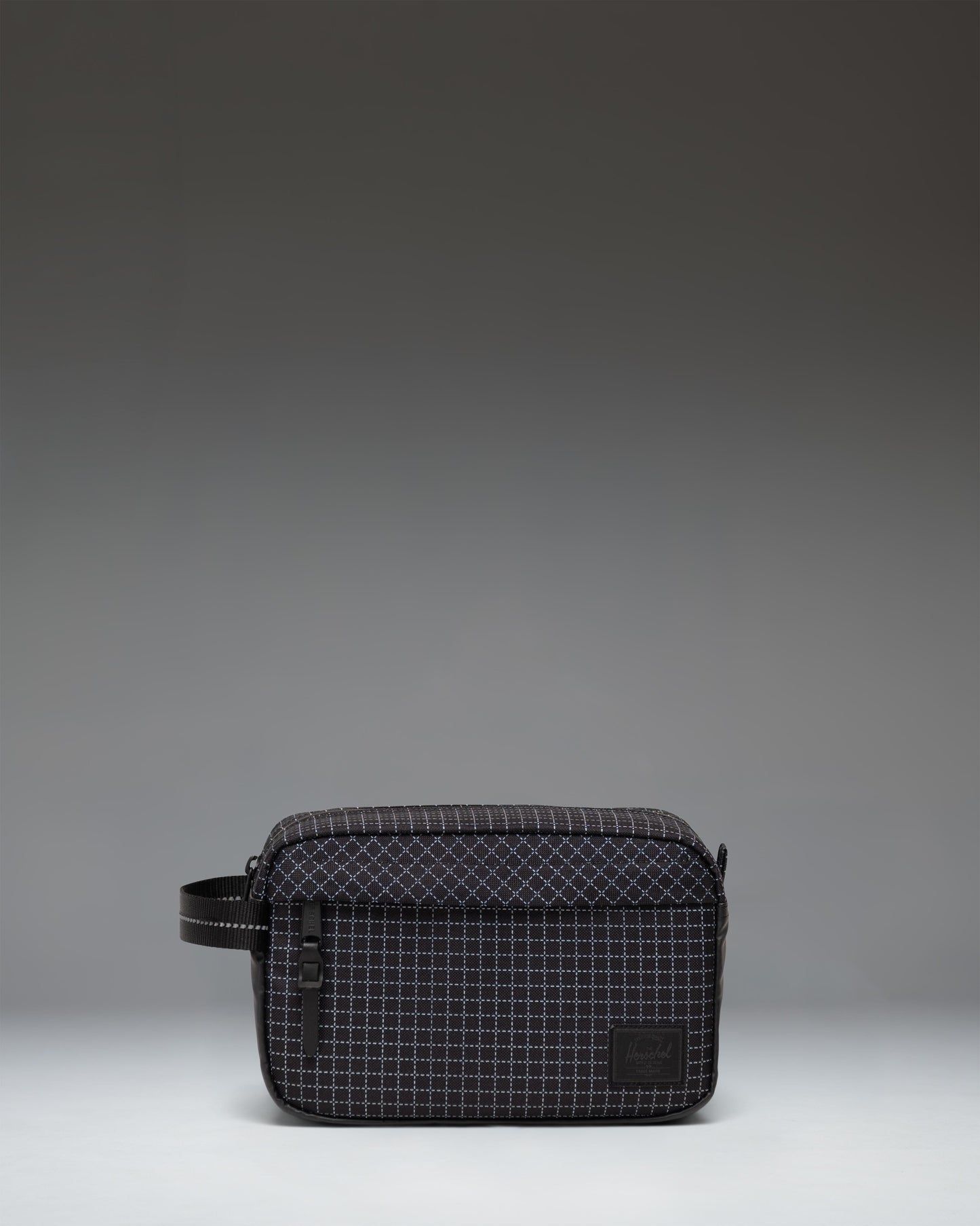 Herschel Supply Co. Chapter Travel Kit in Grid Black/Black featuring a subtle grid pattern, front zippered pocket, and side carrying handle.