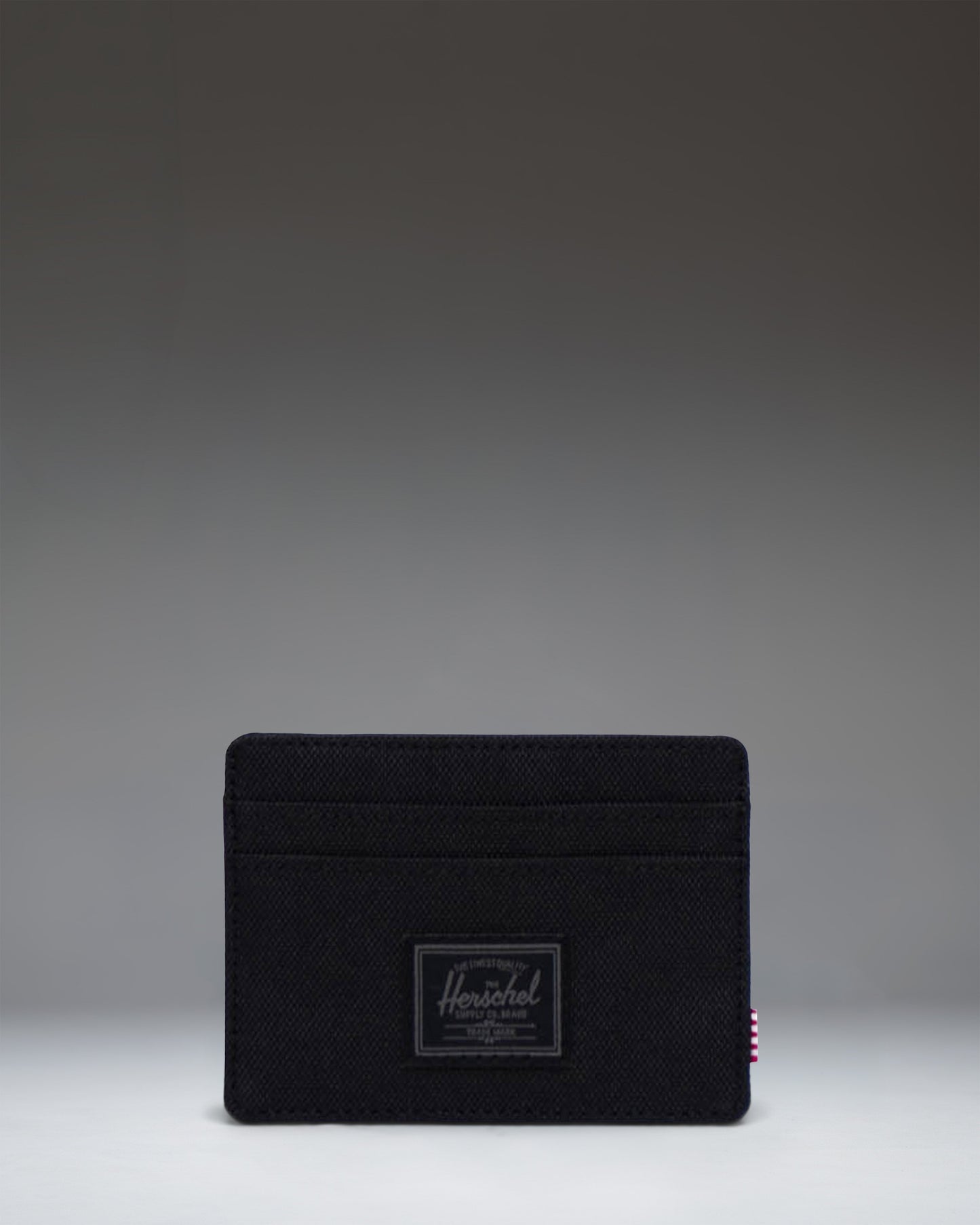 Black Tonal Herschel Supply Co. Charlie Cardholder wallet featuring a minimalist design with multiple card slots and a central storage sleeve.