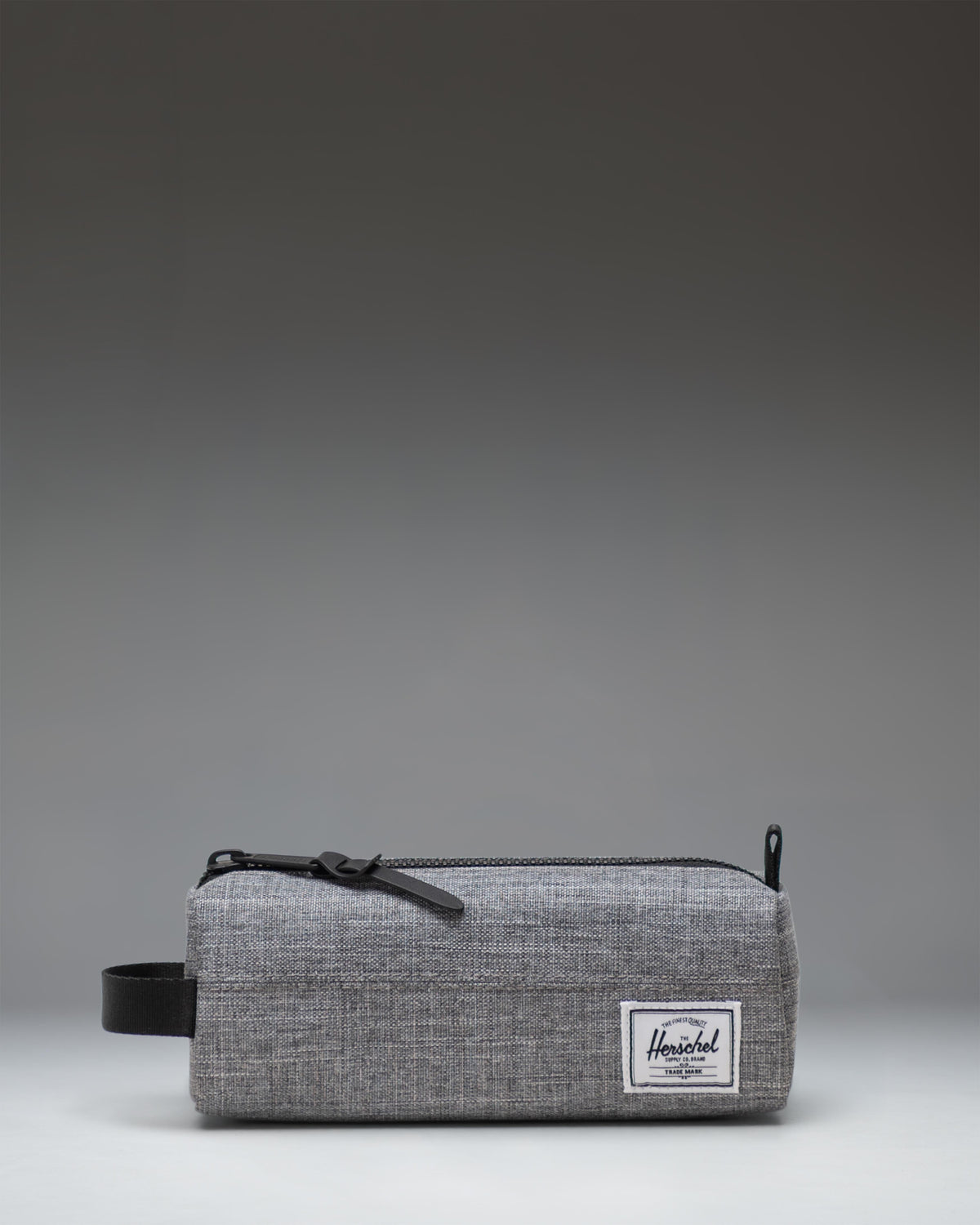 Herschel Supply Co. Settlement Pencil Case in Raven Crosshatch grey, showing a front view with its classic woven label and exposed zipper.