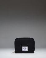 Herschel Supply Co Tyler Wallet in black, displaying a classic zippered design with the signature woven label on the front.