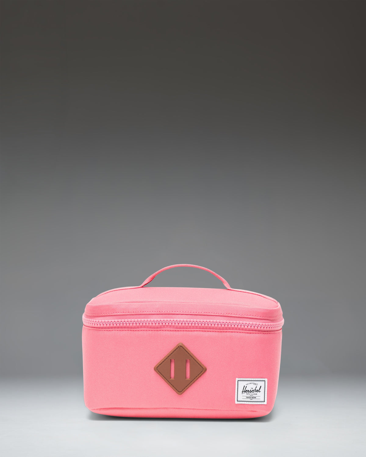 Herschel Supply Co Little Herschel Heritage Lunch Box in Confetti print with a pink front pocket, white logo patch, and top handle.