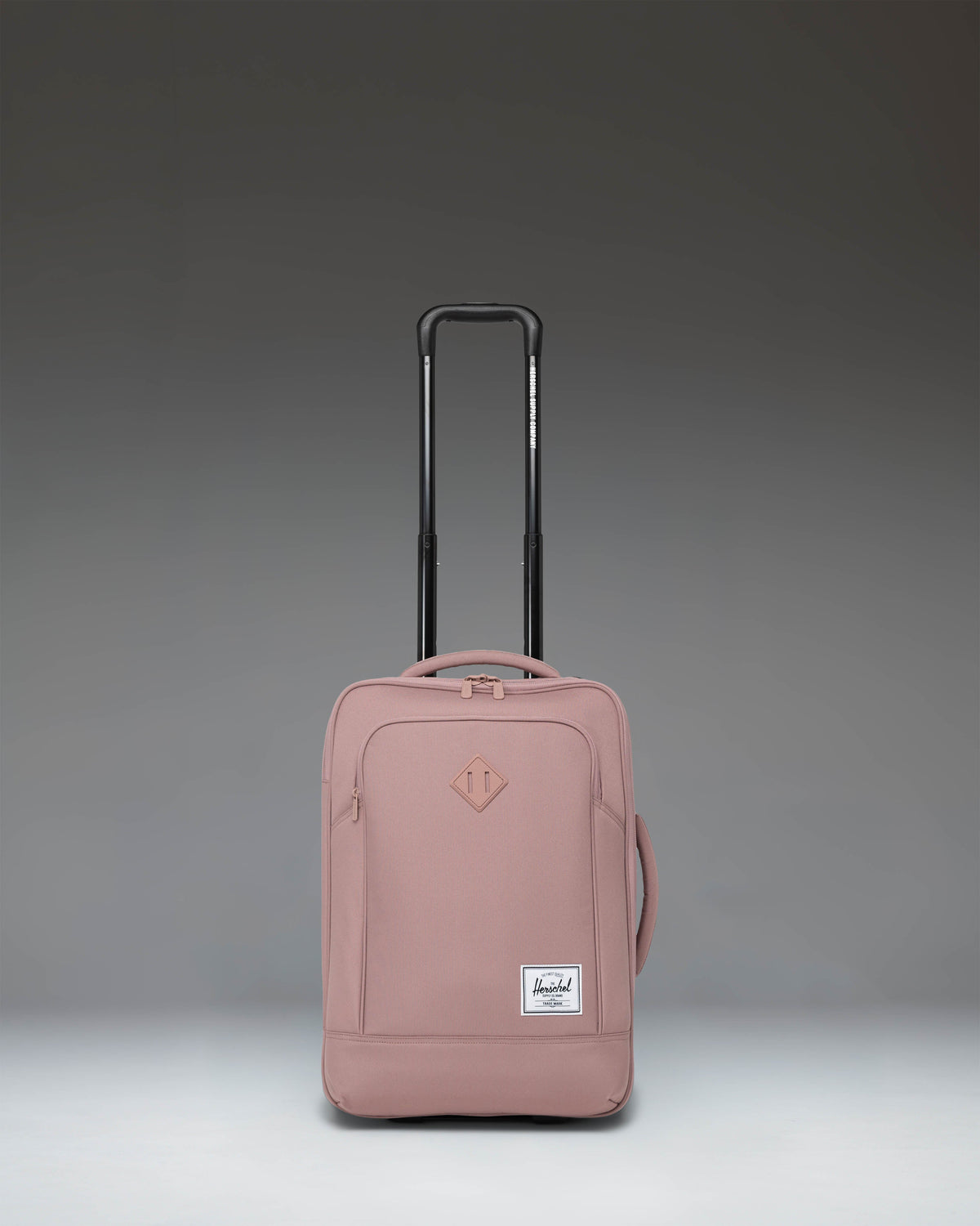 Herschel Supply Co Heritage Softshell Large CarryOn Luggage in Ash Rose pink, showing the front view with wheels and handle.