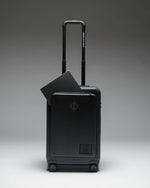 Herschel Heritage Hardshell Pro Large Carry On luggage in Black, shown from the front with a textured hard shell and retractable handle.
