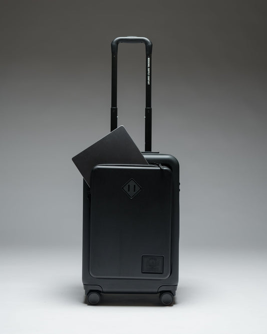 Herschel Heritage Hardshell Pro Large Carry On luggage in Black, shown from the front with a textured hard shell and retractable handle.