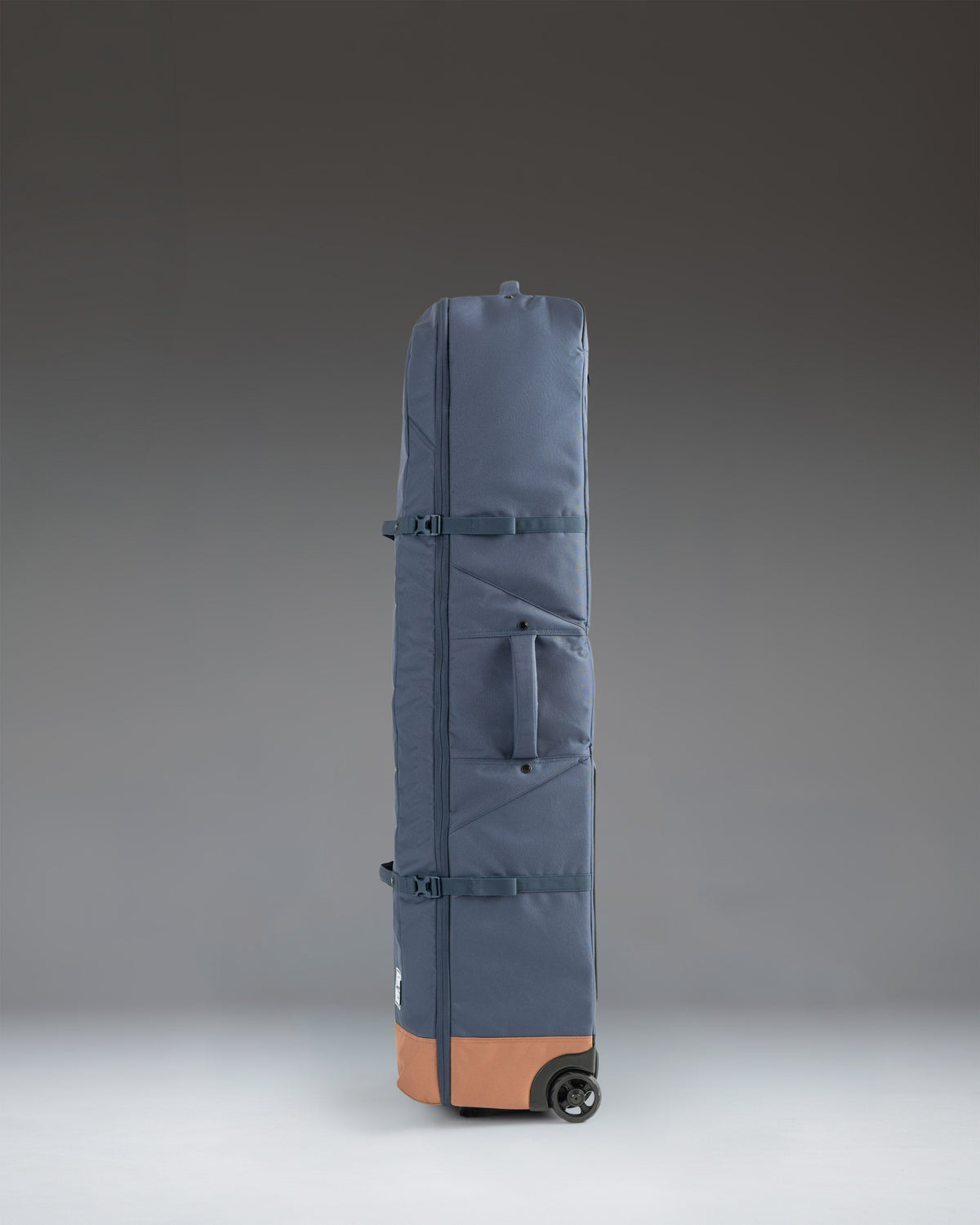 Herschel Heritage Golf Travel Wheelie Bag in Navy and Saddle Brown, showing a side view with wheels and a sturdy handle.