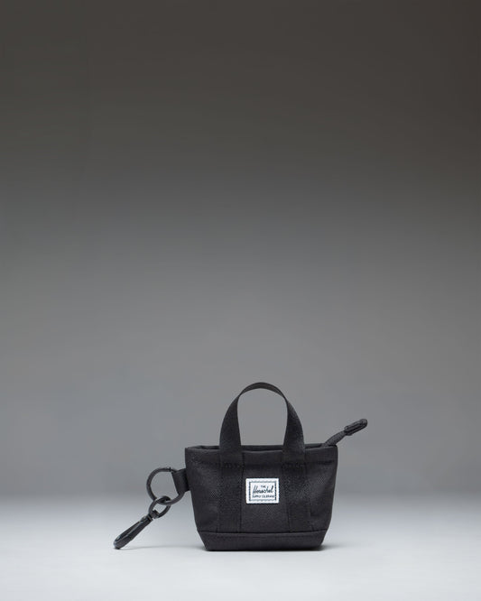 Herschel Supply Co. Heritage Tote Bag Charm in black, featuring a mini zippered tote design with a metal keyring and clip attachment.