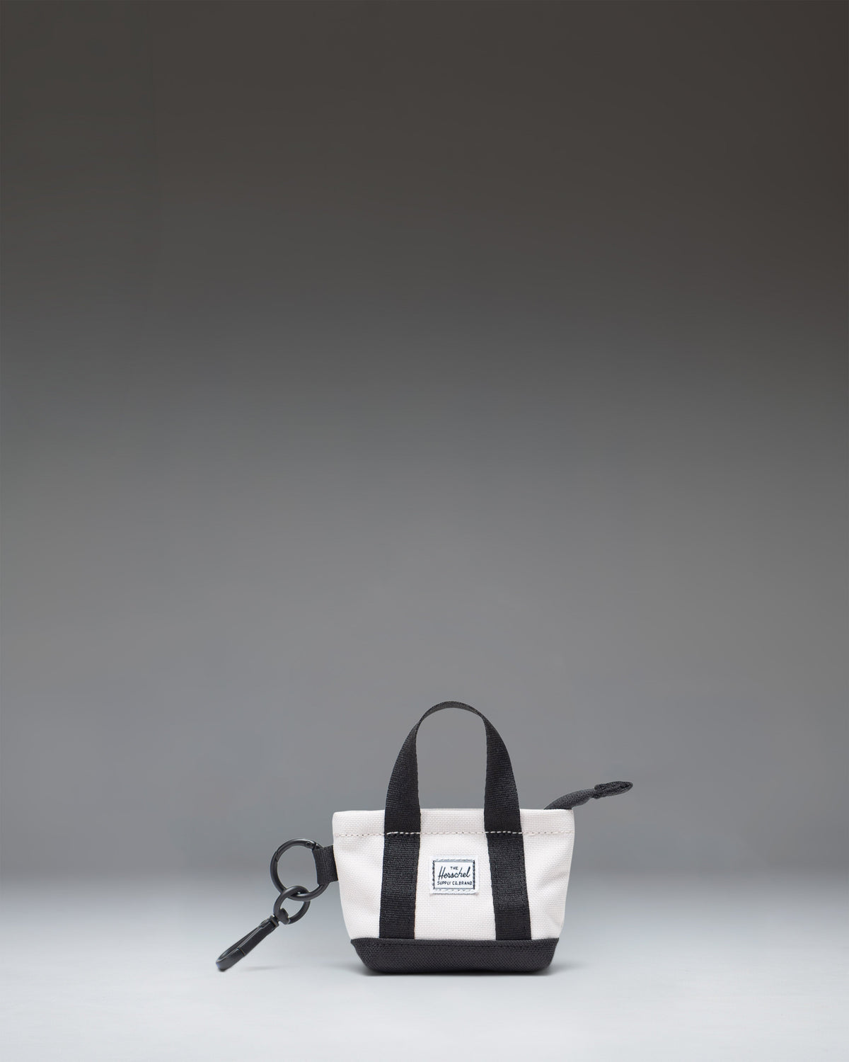 Herschel Supply Co. Heritage Tote Bag Charm in Moonbeam, a miniature cream-white tote bag keychain with a metal clip keyring.