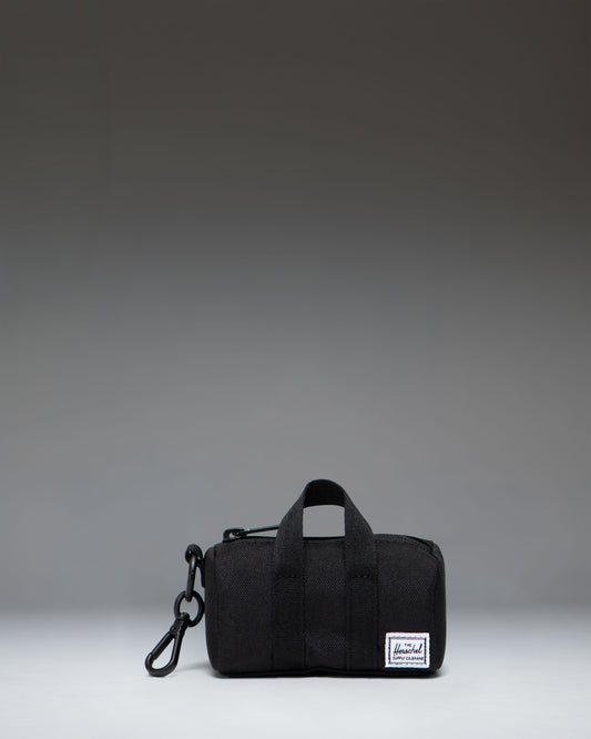 Herschel Novel duffle bag charm in black, showing a miniature version of the classic duffle bag with a zipper closure and top handles.